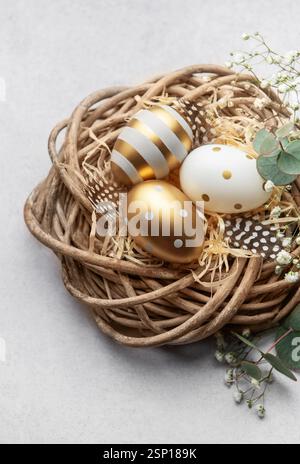 Easter eggs are nestled in a decorative nest, adorned with feathers and delicate gypsophila flowers, creating a festive springtime scene Stock Photo