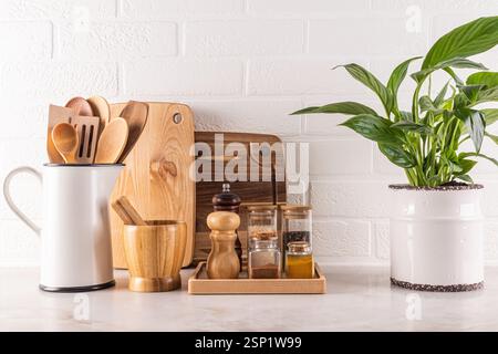 Beautiful kitchen background with spice storage area, cutting wooden boards, green plant in a chic indoor pot. white brick wall.. Front view Stock Photo