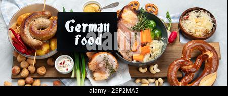 Traditional German cuisine, Schweinshaxe roasted ham hock. Beer, pretzels and various Bavarian specialties on wooden board, on a white background, top Stock Photo