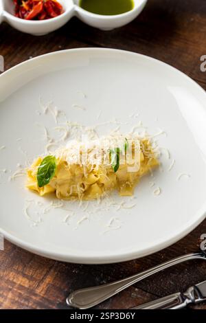 Delicious Italian pasta pappardelle with parmesan in white porcelain plate on wooden table Stock Photo