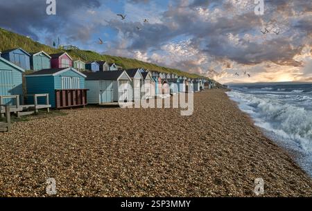 Traditional wooden painted colourful painted beach huts on the shingle beach of Milford on Sea, Hampshire Engalnd, UK Stock Photo