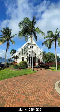 A small white church with a brick driveway is surrounded by palm trees, creating a peaceful island sanctuary for a tropical church wedding venue. Hami Stock Photo