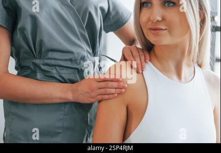 Doing massage. Woman is in health center getting help by doctor. Stock Photo