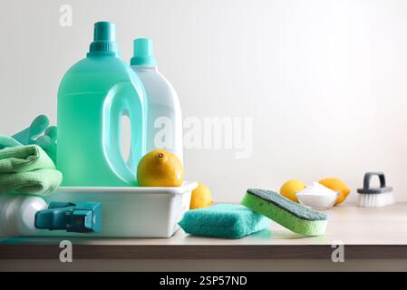 Cleaning products for the house in green tones on wooden bench such as disinfectant, scouring pads, cloth, gloves and lemons with white isolated backg Stock Photo