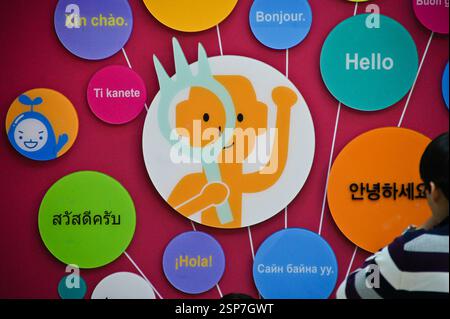 Colorful wall art featuring greetings in various languages. In South Korea, a person holds a magnifying glass, symbolizing curiosity and exploration. Stock Photo