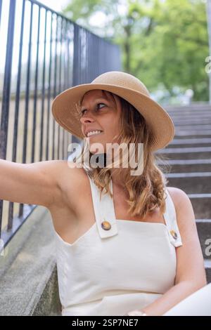Elegant woman relaxing on Parisian stairs in summer fashion. Stock Photo