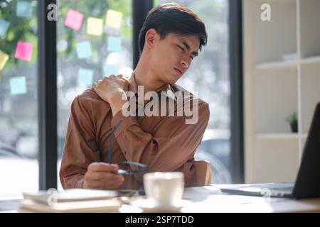 Tired worker experiencing neck and shoulder pain prolonged work hours Stock Photo