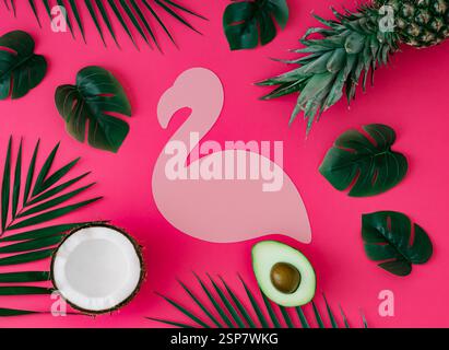 Creative layout with pineapple, coconut, avocado and tropical leaves with pink flamingo paper card note copy space on pink background. Summer tropical Stock Photo