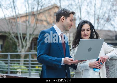 Businessman and businesswoman reviewing information on laptop outdoors Stock Photo