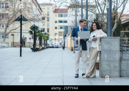 Businesspeople working with laptop and smartphone outdoors in the city Stock Photo