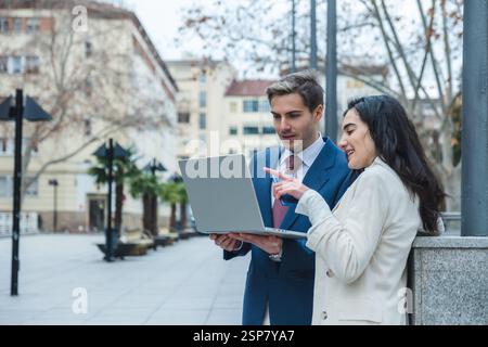 Businesspeople working outdoors using laptop in urban setting Stock Photo