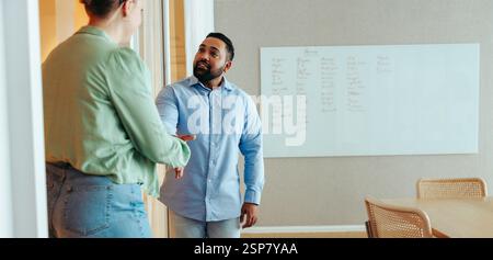 A welcoming handshake between two colleagues. A man in a blue shirt warmly greets a woman, embodying the concept of professional introduction and coll Stock Photo