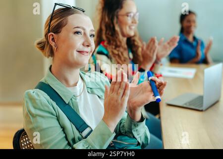 A group of marketing professionals in a casual meeting setting, engaged and applauding. The scene conveys teamwork and appreciation within a modern of Stock Photo