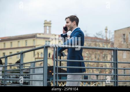 Businessman leaning on railing and talking on mobile phone Stock Photo