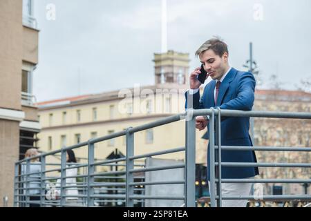 Businessman checking time while talking on phone in urban setting Stock Photo