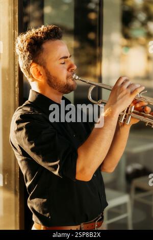 Young musician playing trumpet in golden sunlight Stock Photo