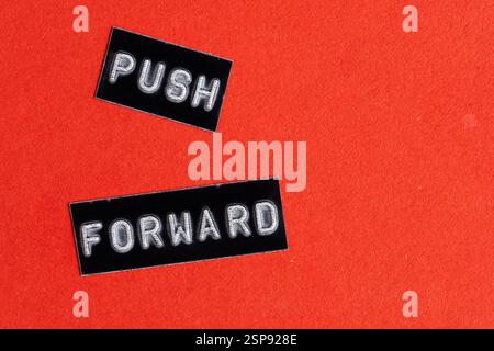 Push forward, word printed on black and white paper with red background. Concept of motivation Stock Photo