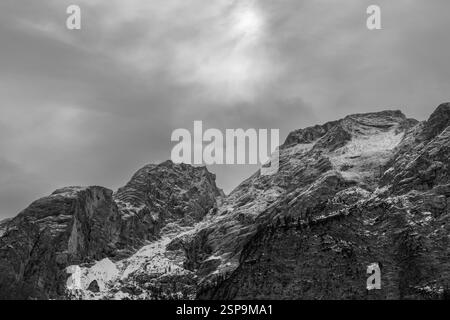 Black and white mountain landscape in the Dolomites featuring rocky cliffs, snow patches and contrasting light and shadow emphasizing rugged textures. Stock Photo
