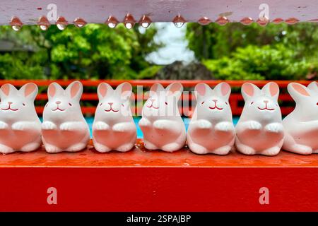 Porcelain rabbits amulets perched on a red shelf in a temple of Kyoto. Stock Photo