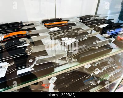 Lviv, Ukraine - February 13, 2025: Various folding knives displayed on shelves in a shop under a glass showcase Stock Photo