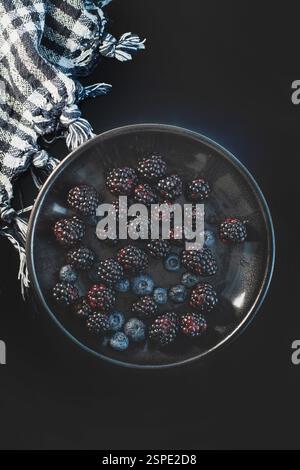 Fresh blackberries and blueberries on a black plate in a dark and moody kitchen setting Stock Photo