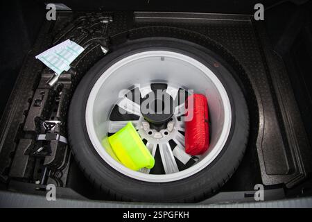 Spare tire, reflective vest, first aid kit and emergency sign in the car trunk under the floor Stock Photo