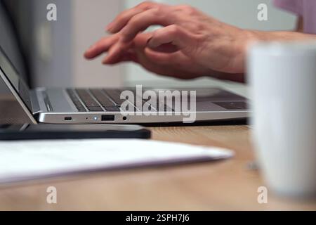 Hands typing on a laptop in a home workspace Stock Photo