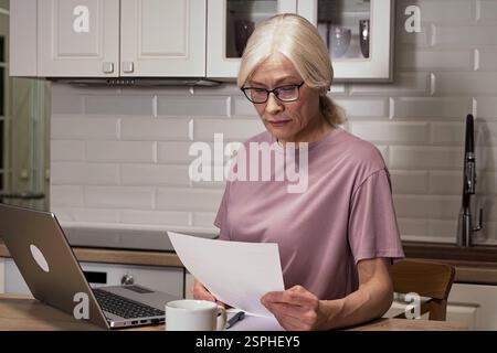 Elderly woman examining important papers at home Stock Photo