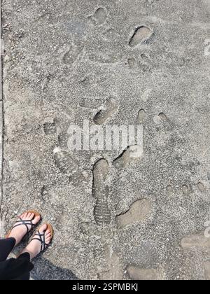 A person is standing on a sidewalk which has footprints on it Stock Photo