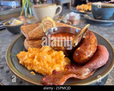 Delicious full English breakfast or sausage, bacon, baked beans, scrambled eggs and toast Stock Photo