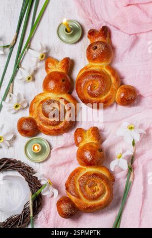 Easter composition made of rabbits, painted eggs and spring bouquets. Bunches made of yeast dough on a lilac background, rustic style, selective focus Stock Photo