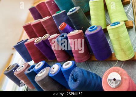 Vibrant spools of thread arranged creatively in a sewing studio filled with inspiring colors and textures during daylight hours Stock Photo