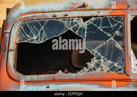 Broken windshield glass in an old abandoned truck. Split windshield in an orange truck. Stock Photo