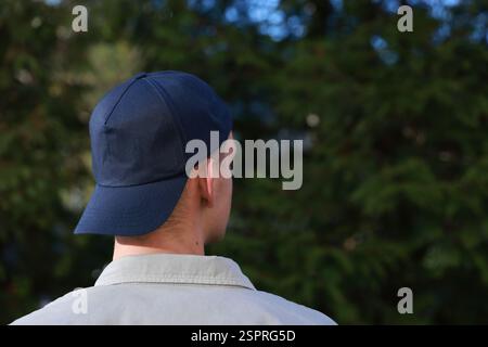 Man in stylish baseball cap outdoors, back view. Mockup for design Stock Photo