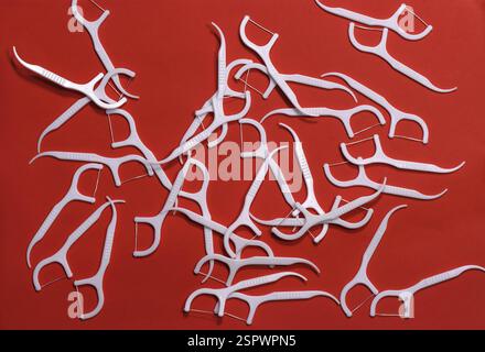 Image of white toothpicks with a thread on a red background. Stock Photo