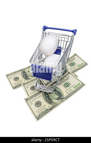 Vertical shot of a tiny shopping cart with two eggs in it and three one hundred dollar bills underneath it. Stock Photo
