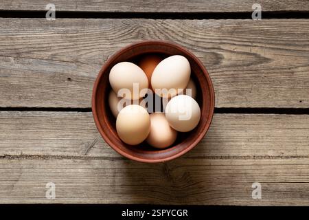Brown chicken eggs in a clay bowl on a wooden table, eggs Stock Photo