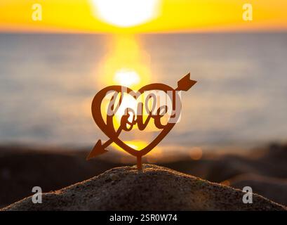 Black silhouette of stick with the words Happy Birthday in rectangular frame on background of sea and sea waves during sunset sunrise with sunrise or setting sun close-up. Concept holiday celebration Stock Photo