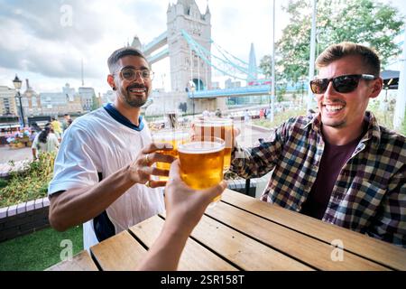 Friends toasting with beer glasses at tower bridge in london, uk Stock Photo