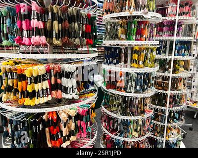 Lviv, Ukraine - February 13, 2025: Brightly organized embroidery threads displayed on racks in a craft store setting Stock Photo
