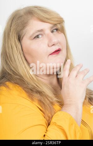 Close-up portrait of a mature plus-size woman with blonde hair, green eyes, and red lipstick. Stock Photo