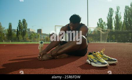 African American man feel ache painful leg pain injured foot after workout outdoors male sportsman footballer guy suffer injury bone finger callus Stock Photo