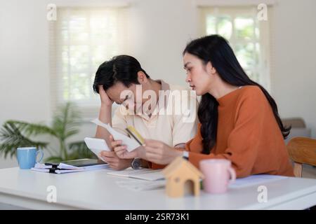 Concerned couple reviewing bills and income calculations, facing financial challenges. Stock Photo