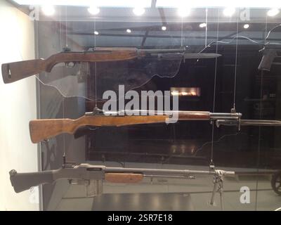 Three rifles and a submachine gun displayed in a glass case. Garand, M14, M1 Carbine, Thompson. These firearms used by the United States military in v Stock Photo