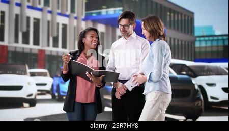 Customers choosing new car with dealer at dealership showroom.  Family discussing terms with finance manager for contract signing. Stock Photo