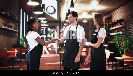 Multiracial team celebrates successful new chef at busy restaurant cafe. Stock Photo