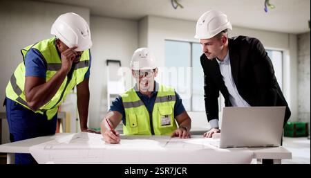 Young businessmen and engineers collaborate on apartment construction project site. Stock Photo
