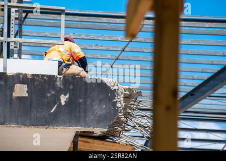 A worker in high vis clothing and a safety harness, working on a construction and demolition site in Sydney, Australia Stock Photo