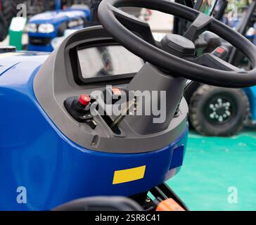 Operator controls of industrial equipment. Close-up of vehicle control panel with steering wheel, buttons, and lever in a compact loader Stock Photo
