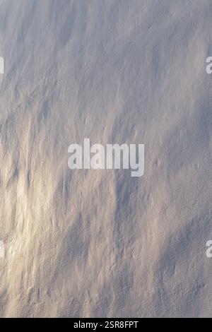 Close-up of a clean and uneven stone wall painted in white. Beautiful warm sidelight creates soft shadows. Abstract textured background, copy space. Stock Photo